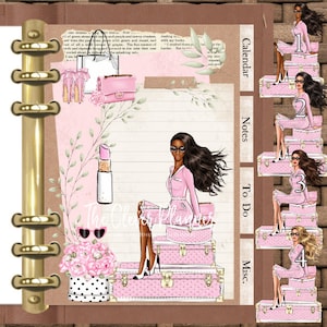 May include: A pink and white planner with a gold ring binder. The cover features a woman sitting on a stack of pink suitcases with a floral design. The planner has tabs for calendar, notes, to do, and misc.