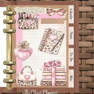 May include: A planner with a brown cover and gold rings, featuring illustrations of a makeup bag, glasses, perfume, a notebook, a handbag, and a stack of books, all with a leopard print design and pink accents. The text "The Clever Planner" is visible.