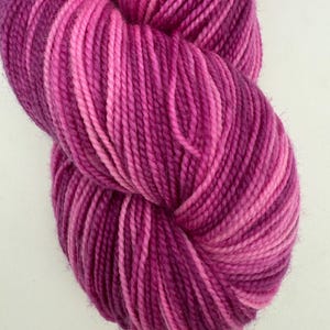 May include: A skein of pink and purple yarn with a variegated color pattern.