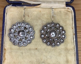 May include: A pair of silver earrings with a circular design. The earrings are in a blue velvet jewelry box.
