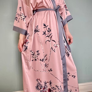 May include: A pink satin robe with a floral print and a gray satin sash.