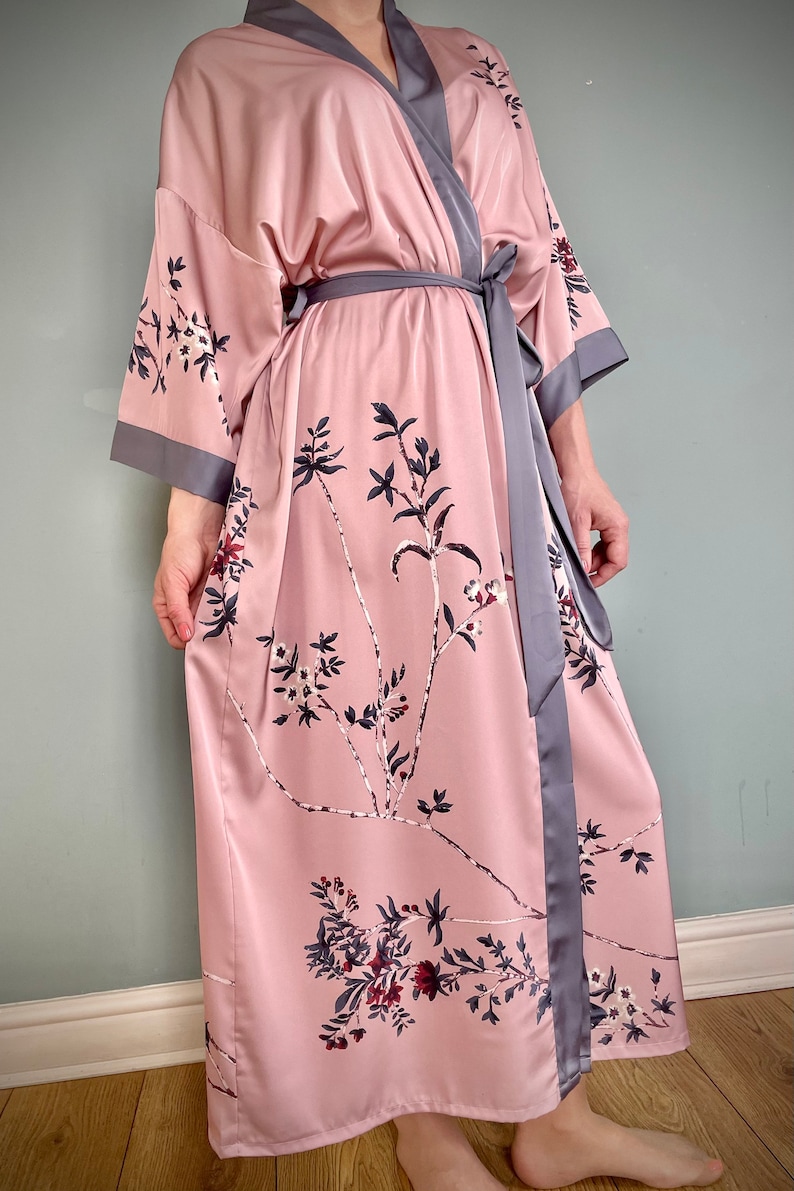 May include: A pink satin robe with a floral print and a gray satin sash.