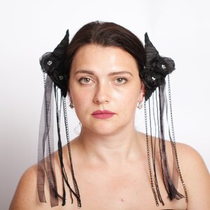 Puede incluir: Accesorio para el cabello negro con un diseño floral y cadenas colgantes. El accesorio se lleva en el lateral de la cabeza.