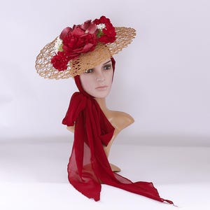 May include: A straw hat with a red and white flower embellishment and a matching red scarf.