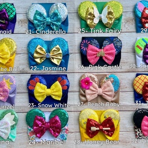 May include: A set of 12 colorful headbands with character-themed ears and bows. The headbands feature characters like Ariel, Cinderella, Tinkerbell, Stitch, Belle, Jasmine, Rapunzel, Snow White, Tiana, Maribel, Honey Bear, and Pink Cheetah.