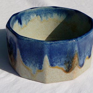 May include: A blue and white ceramic bowl with a geometric shape. The bowl has a glazed finish with a drip effect.