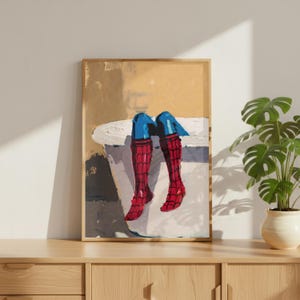 May include: A framed painting depicts a figure in a bathtub, with only the legs visible. The legs are clad in red and blue superhero attire. The artwork is displayed on a wooden cabinet, with a potted plant in the background.