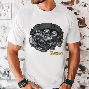 May include: White t-shirt featuring a detailed illustration of a car engine with the word "Boxer" in yellow. The engine is depicted in shades of gray, black, and silver, with blue accents. The shirt also has the text "Ships Next Day" in the upper left corner.
