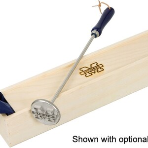 May include: A silver metal branding iron with a blue wooden handle and the University of Michigan logo. The branding iron is in a wooden box with the University of Michigan logo.