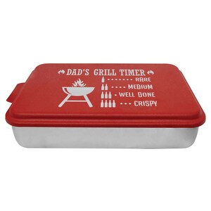 May include: Red metal baking pan with a white lid. The lid has a graphic of a grill with flames and the text "Dad's Grill Timer" with a list of doneness levels: Rare, Medium, Well Done, Crispy.