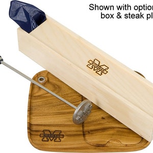 May include: A wooden box with a blue bandana inside, a wooden steak board with a metal steak pounder, and a metal skewer with a blue and yellow handle. The box and board are both engraved with the University of Michigan logo.