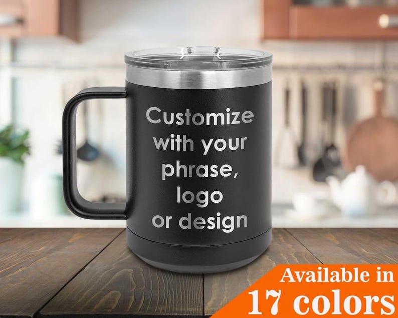 May include: Black travel mug with a handle and a silver lid. The mug has the text "Customize with your phrase, logo or design" in silver lettering. The bottom right corner has the text "Available in 17 colors" in white lettering on an orange background.