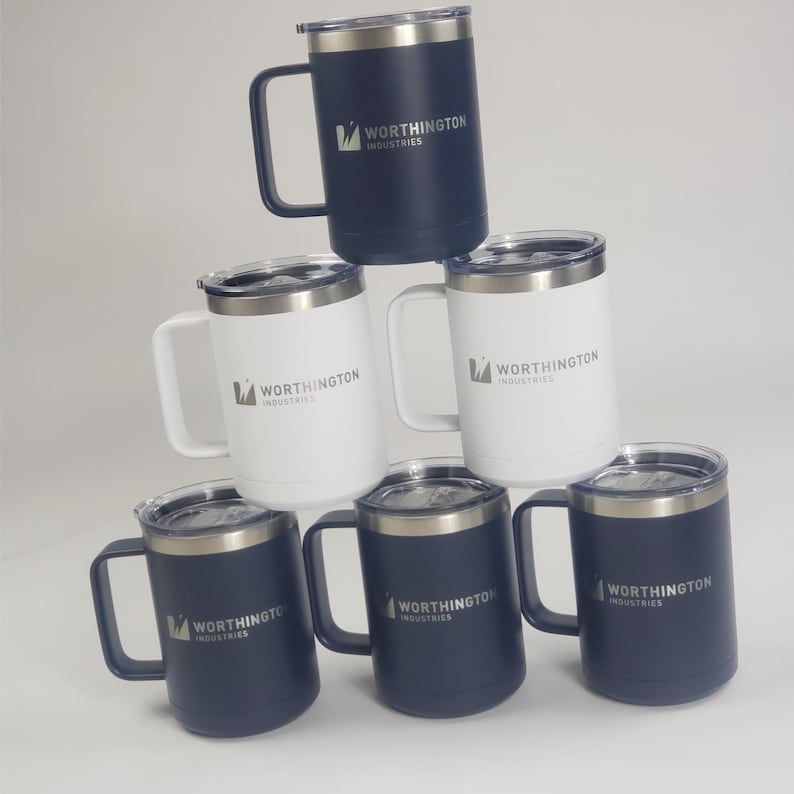 May include: A stack of insulated travel mugs in navy blue and white. Each mug has a silver rim, a handle, and a clear lid. The Worthington Industries logo is printed on the side of each mug.