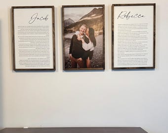 May include: Three framed prints on a white wall above a dark brown dresser. The center print is a photograph of a couple embracing in a mountainous landscape. The prints on either side are text-based, with the names "Jacob" and "Rebecca" written in cursive.