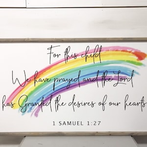 May include: A framed wooden sign with the text "For this child We have prayed and the Lord has Granted the desires of our hearts" and a watercolor rainbow. The text "1 Samuel 1:27" is at the bottom.
