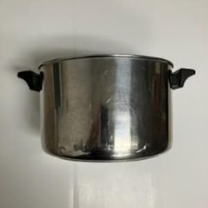 May include: A cylindrical stainless steel cooking pot with a polished metallic finish. The pot features two black plastic handles attached to opposite sides of the upper rim. The design is simple and functional with a flat base and straight walls.