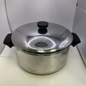 May include: Stainless steel pot with a lid and black handles. The pot has a shiny, reflective surface and a black knob on the lid. The handles are on either side of the pot.