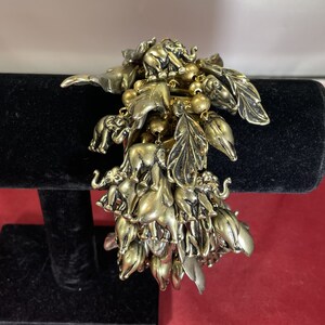 May include: A gold and silver charm bracelet featuring a cluster of elephant charms and leaf-shaped charms.