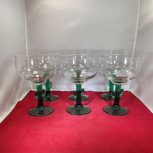 May include: Set of six clear glass margarita glasses with green cactus-shaped stems. The glasses are arranged in two rows of three.