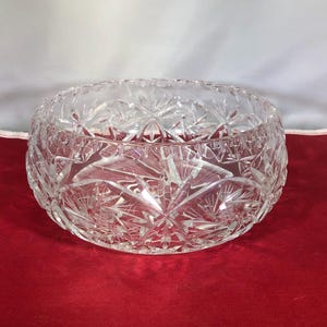 May include: A clear glass bowl with a cut crystal design. The bowl is round and has a wide rim.