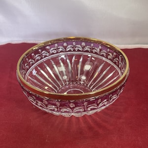 May include: A clear glass bowl with a gold rim and purple floral design. The bowl has a fluted design and is perfect for serving fruit or snacks.