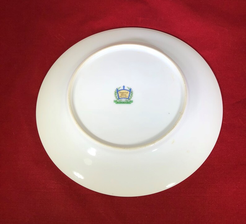 May include: White ceramic plate with a green and blue logo that reads "Imperial China, Made in Japan".