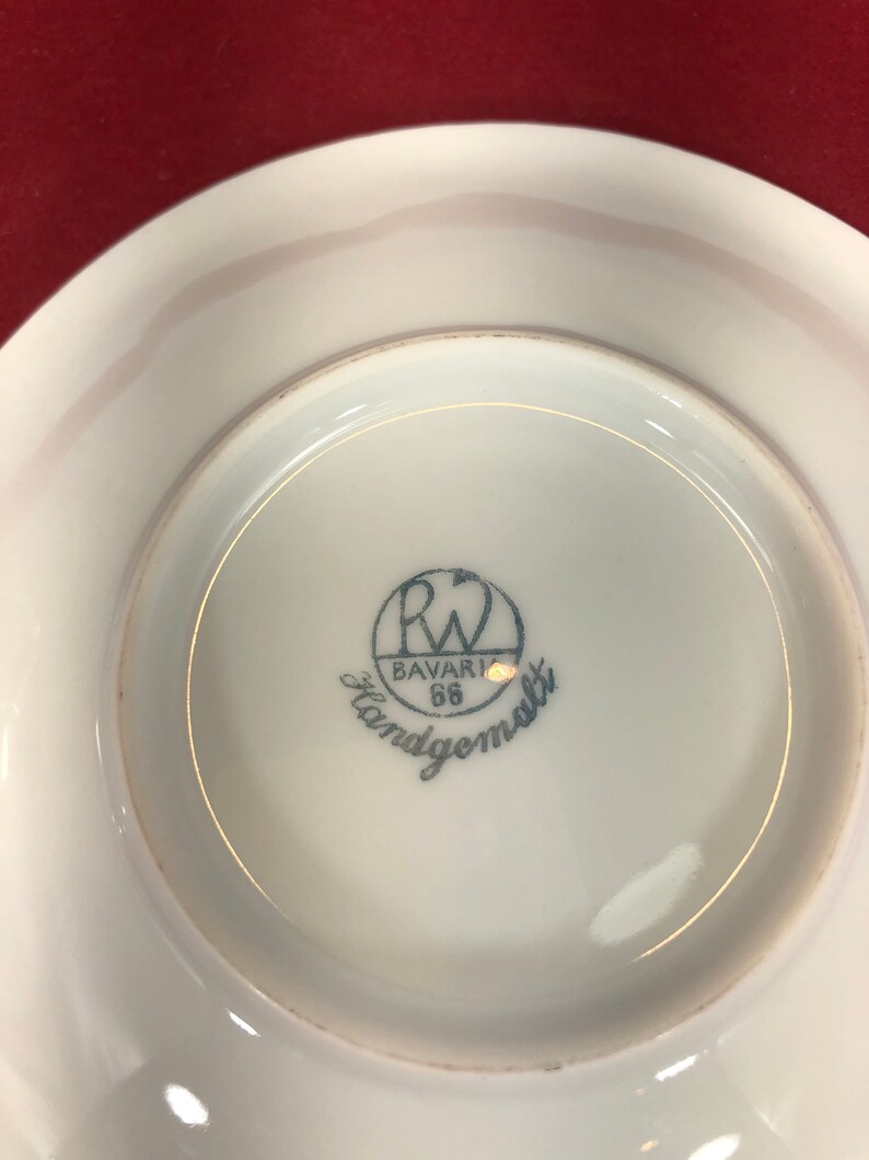 May include: A white porcelain saucer with a blue and white logo that reads "R.W. Bavaria 66 Handgemalt".