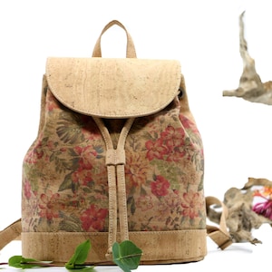 May include: A small, cork backpack with a floral print in shades of red, pink, and green. The backpack has a drawstring closure and a flap with a buckle.