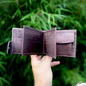 May include: A brown cork leather wallet with multiple compartments and a flap closure. The wallet is open and the inside is visible. The text "MODEL DEAN DARK" is visible on the bottom right corner of the image.