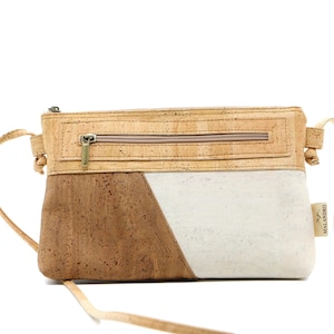 May include: A crossbody bag made of cork with a diagonal color block design. The top section and the lower left side are brown, while the lower right side is white. It has a zipper closure and a long strap.