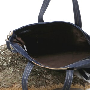 May include: A navy blue tote bag with a brown lining and a zipper closure. The bag has two top handles and a detachable shoulder strap.