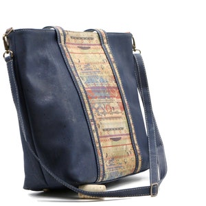 May include: A blue cork leather tote bag with a patterned cork strap. The bag has a long shoulder strap and a top zipper closure.