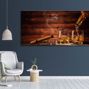 May include: A wooden background with two glasses of amber liquid, one being poured from a bottle. A cigar rests on the surface in front of the glasses.