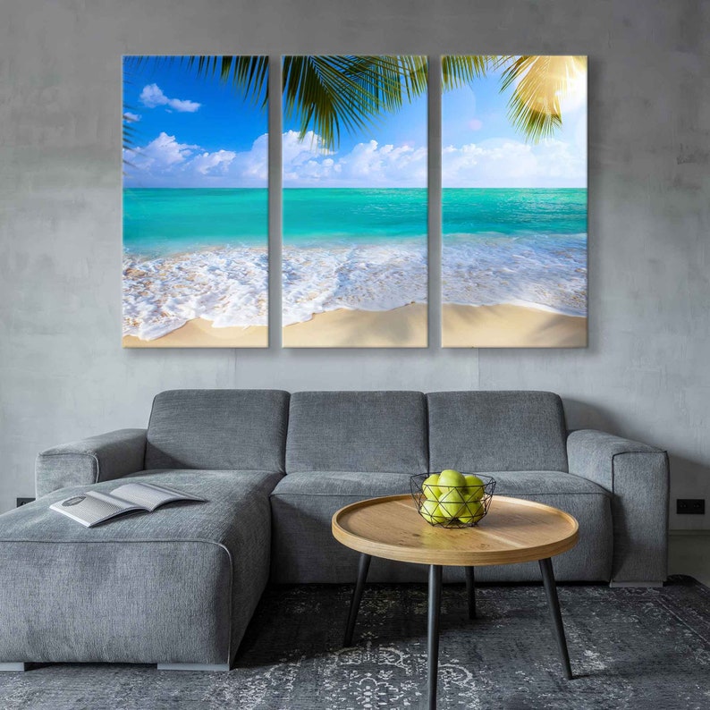 May include: A three-panel canvas print depicting a tropical beach scene with turquoise water, white sand, and palm tree leaves. The panels are arranged horizontally, creating a panoramic view of the beach.