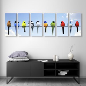 May include: A vibrant multi-panel canvas print features ten colorful birds perched on a wire against a light blue sky. The birds are predominantly red, yellow, blue, and green, with some black and white accents. The artwork is a modern and cheerful depiction of nature, suitable for home or office decor. The image is divided into five panels, creating a panoramic effect. The birds are realistically rendered, showcasing their unique plumage and postures. The overall aesthetic is clean and contemporary, with a focus on bright colors and simple composition.