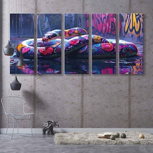 Op de afbeelding: Een kleurrijke slang met roze, blauwe, groene en gele schubben is om een met graffiti bespoten muur gewikkeld. De slang bevindt zich gedeeltelijk in het water en reflecteert de kleuren van de slang en de muur.