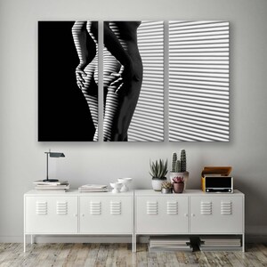 Puede incluir: Una fotograf&iacute;a en blanco y negro de una persona de pie frente a una ventana con persianas. La persona est&aacute; de espaldas a la c&aacute;mara y su cuerpo est&aacute; parcialmente oculto por las persianas.