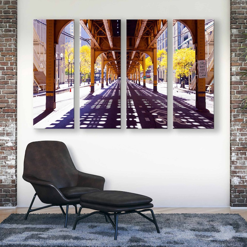 May include: A three-panel canvas print of a city street under a yellow bridge. The street is lined with trees and the shadows of the bridge create a pattern on the pavement. The sign on the right side of the image reads "May Use Full Lane".