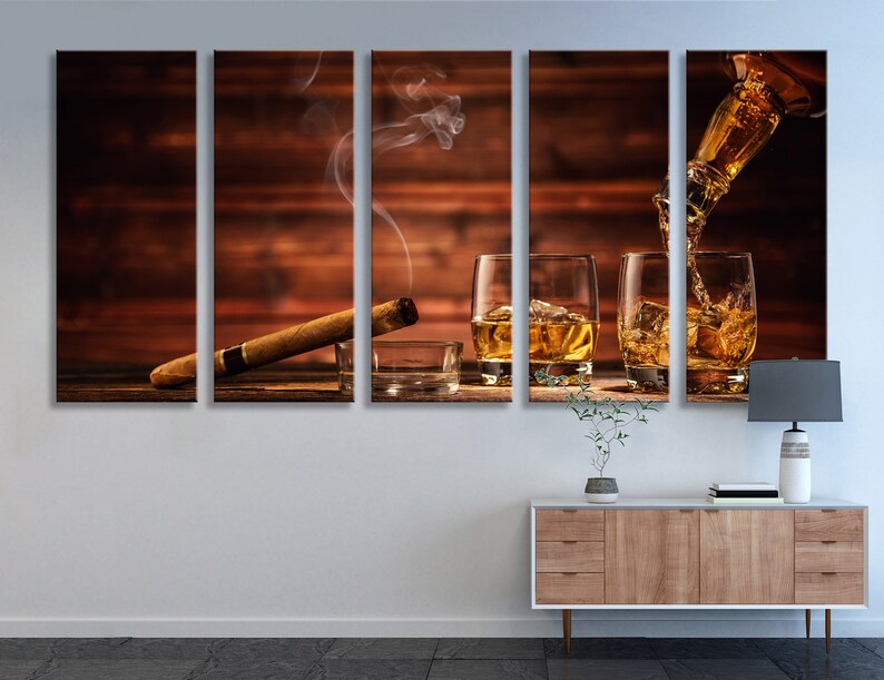 May include: A multi-panel canvas print featuring a wooden background with three glasses of amber liquid, a lit cigar, and a bottle pouring liquid into one of the glasses.