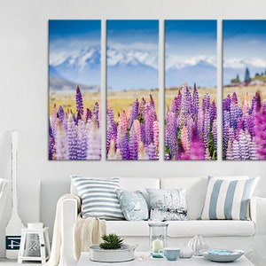 May include: A multi-panel canvas print depicting a field of purple and pink lupin flowers in bloom. The background features a mountain range with snow-capped peaks and a blue sky.