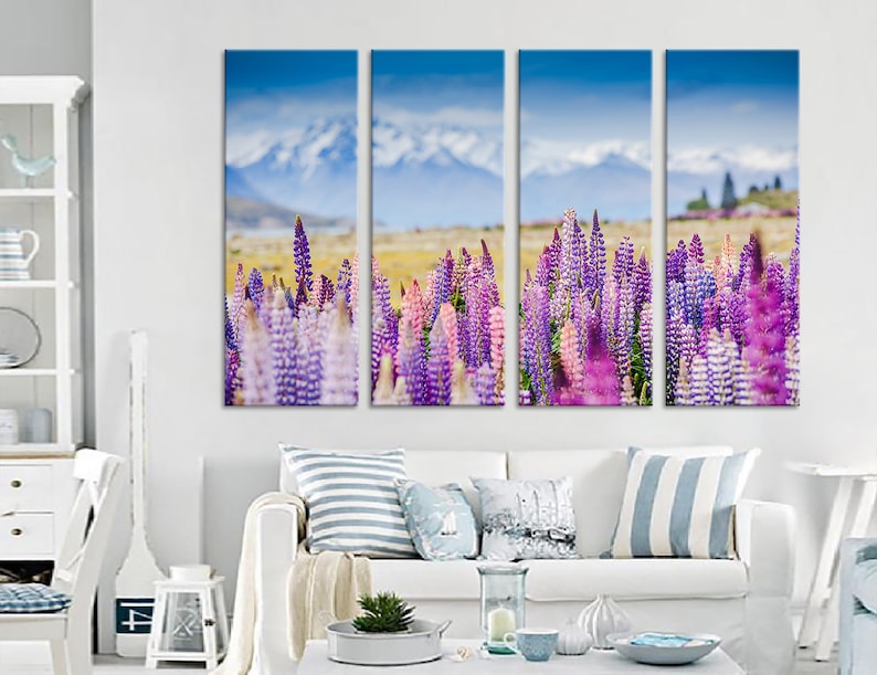 May include: A multi-panel canvas print depicting a field of purple and pink lupin flowers in bloom. The background features a mountain range with snow-capped peaks and a blue sky.