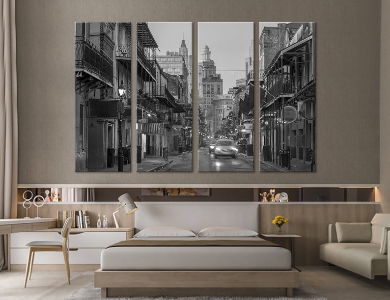 May include: A black and white canvas print set depicting a street scene with buildings and balconies. The image shows a street with cars and buildings with balconies. The artwork is displayed above a bed in a bedroom.