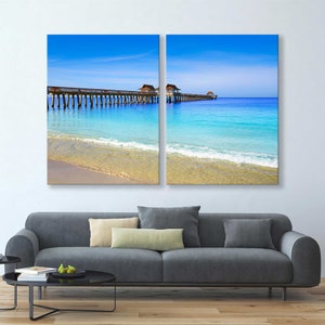 May include: A split-level photograph of a wooden pier extending into a turquoise ocean with a sandy beach in the foreground. The sky is a bright blue with white clouds.