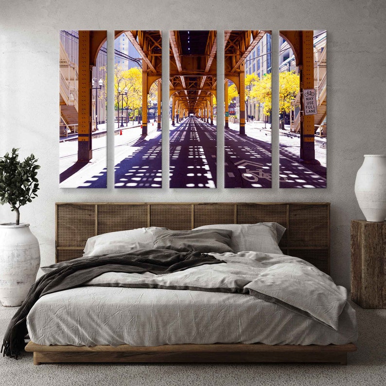 May include: A four-panel canvas print of a city street under a yellow elevated train track. The street is lined with trees and the shadows of the train track create a pattern on the pavement. The sign on the right side of the image reads "May Use Full Lane".