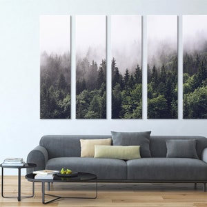 Puede incluir: Una impresi&oacute;n en lienzo de cinco paneles que representa una escena de bosque brumoso con &aacute;rboles verdes altos. La impresi&oacute;n est&aacute; colgada en una pared blanca sobre un sof&aacute; gris.