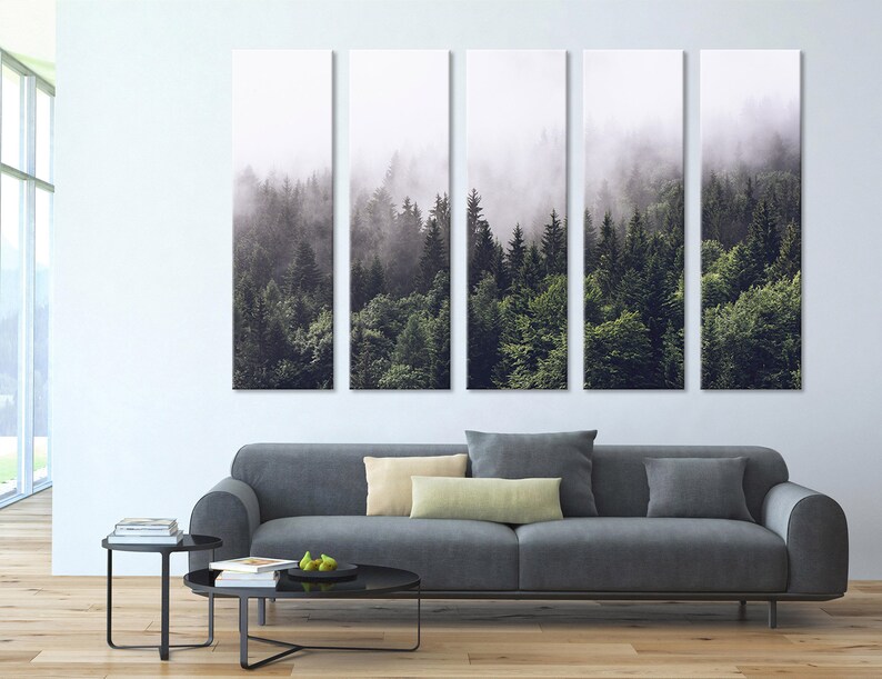 Puede incluir: Una impresi&oacute;n en lienzo de cinco paneles que representa una escena de bosque brumoso con &aacute;rboles verdes altos. La impresi&oacute;n est&aacute; colgada en una pared blanca sobre un sof&aacute; gris.