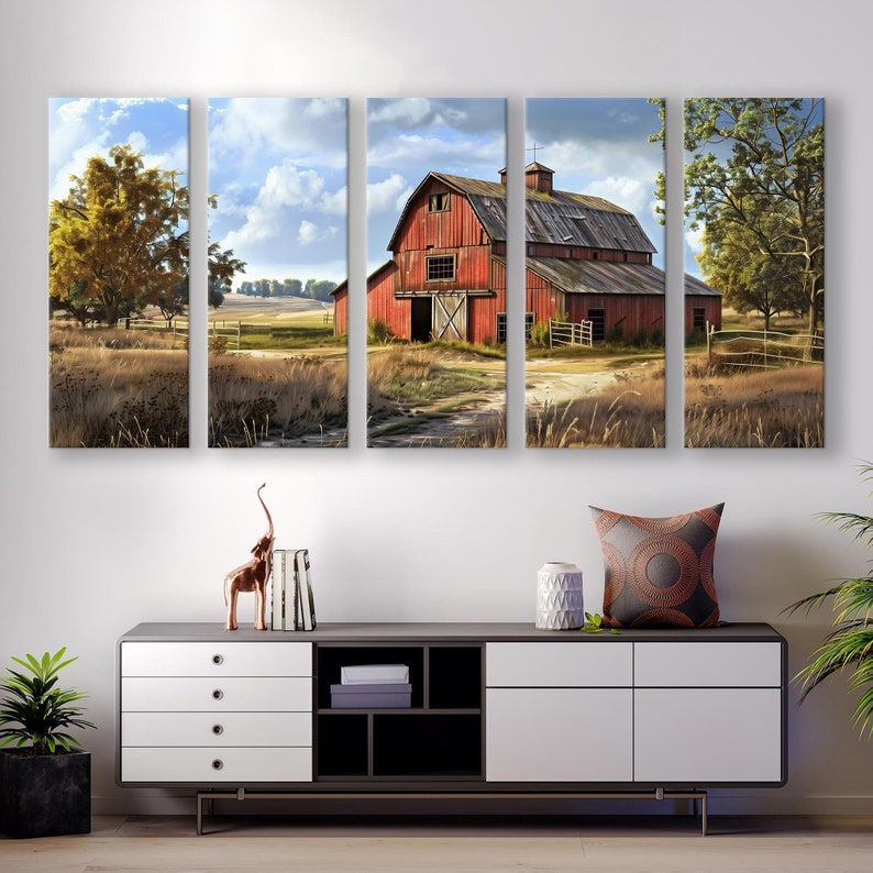 May include: A five-panel canvas art piece depicting a rural landscape with a red barn as the focal point. The barn is surrounded by fields and trees under a cloudy sky. The artwork is displayed above a modern cabinet with decorative items.