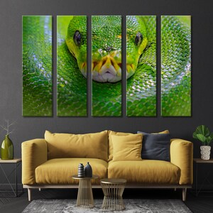 May include: A close-up of a green snake's head with its eyes open and mouth closed. The snake is wrapped around a branch or log, and its scales are visible. The background is a dark green.