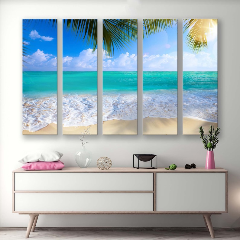 May include: A four-panel canvas print depicting a tropical beach scene. The image features a bright blue ocean with white foamy waves crashing on a sandy shore. Palm tree leaves are visible in the foreground, creating a sense of depth and tropical ambiance.