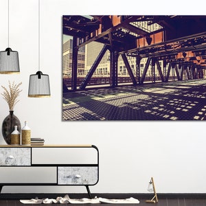 May include: A vintage photograph of a metal bridge over a city street. The bridge is made of steel beams and has a grid pattern on the surface. The photo is taken from below the bridge, looking up at the underside.